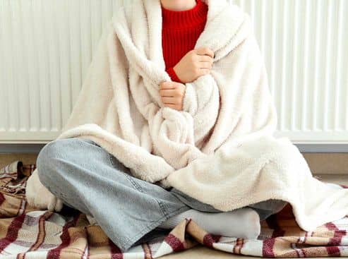 Personne à côté d'un radiateur ayant froid dans son logement
